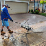 Technician pressure washing a residential driveway to remove dirt and stains, improving curb appeal for a Florida Keys home.