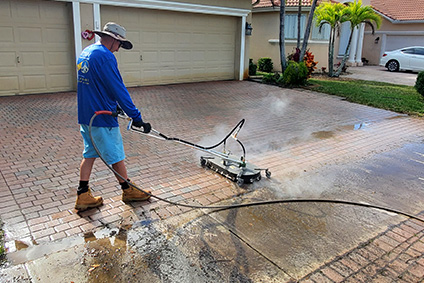 Technician pressure washing a residential driveway to remove dirt and stains, improving curb appeal for a Florida Keys home.