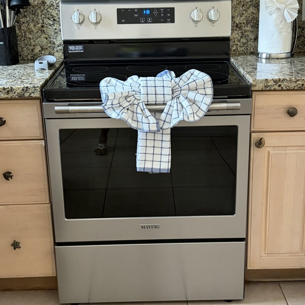 A guest-ready vacation rental kitchen featuring a clean stainless steel Maytag range, granite countertops, and welcoming blue and white checked kitchen towels