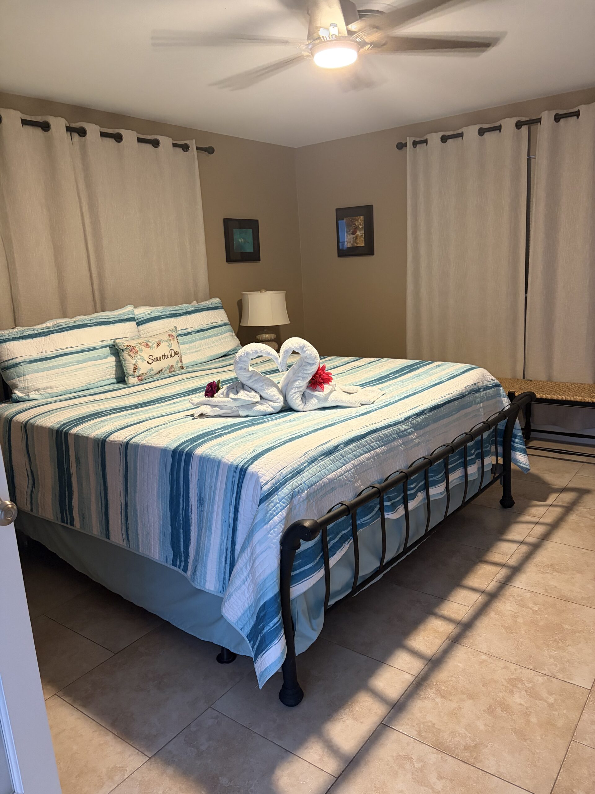 Professionally cleaned vacation rental bedroom in Marathon FL with fresh linens, towel swans and tropical decor by Lee Lapid Housekeeping.
