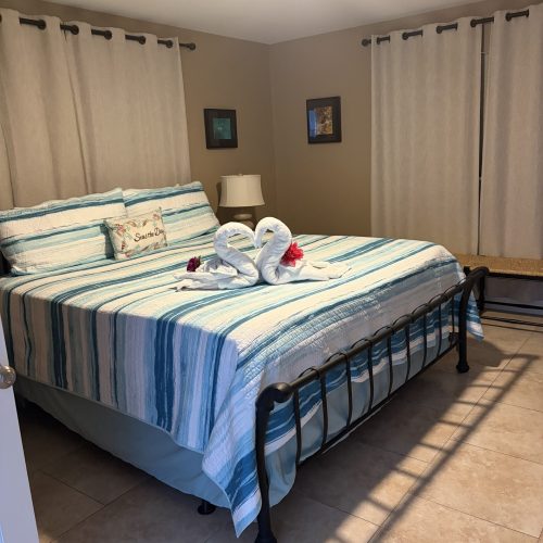 Professionally cleaned vacation rental bedroom in Marathon FL with fresh linens, towel swans and tropical decor by Lee Lapid Housekeeping.